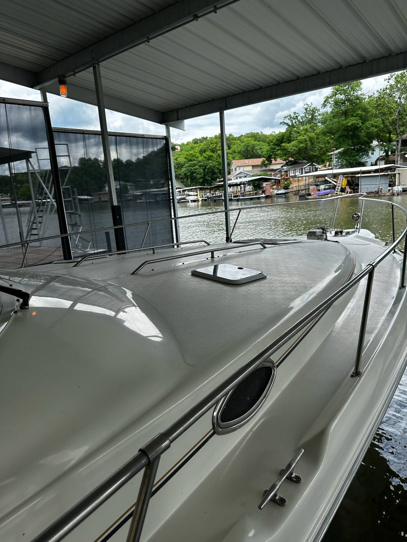 The same boat bow after detailing, with glossy white gelcoat reflecting the boat dock